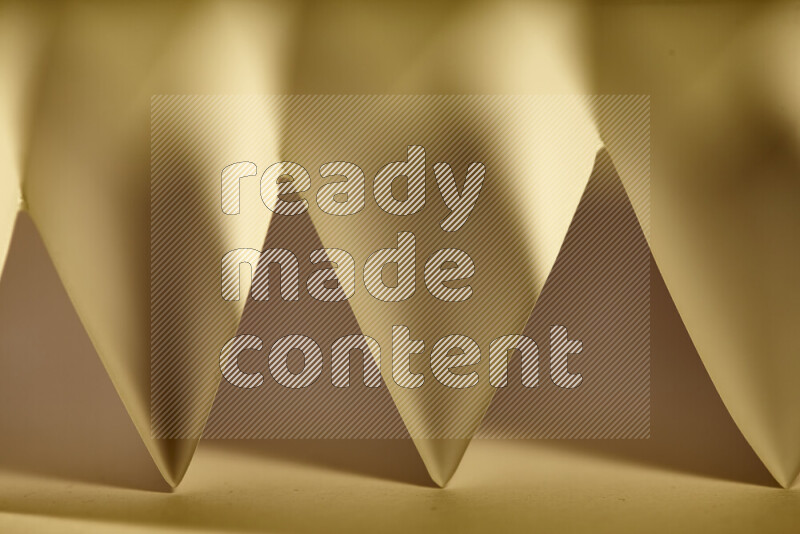 A close-up abstract image showing sharp geometric paper folds in warm gradients