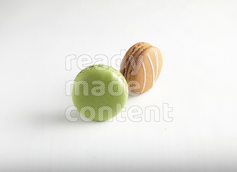 45º Shot of of two assorted Brown Irish Cream, and Green Pistachio macarons on white background