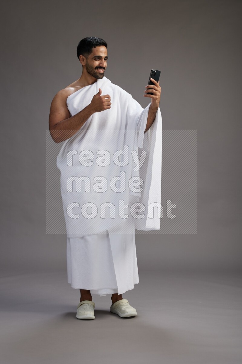 A man wearing Ehram Standing taking selfie on gray background