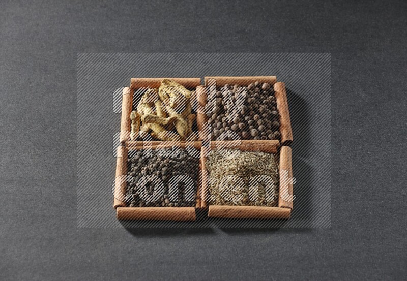 4 squares of cinnamon sticks full of black pepper, cumin, allspice and turmeric fingers on black flooring