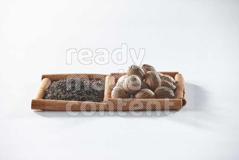2 squares of cinnamon sticks full of black tea and nutmegs on white flooring