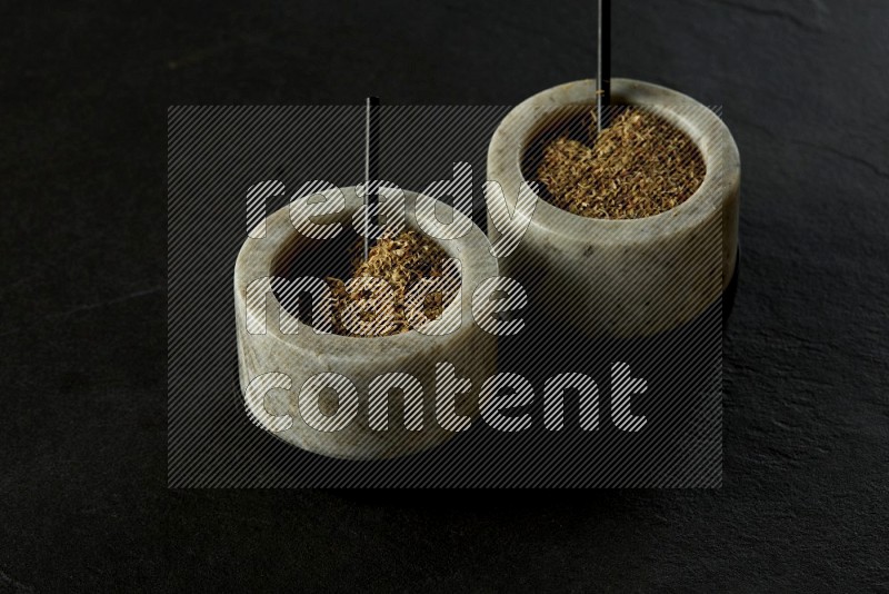 black and white round marble containers filled with herbs on gray textured countertop