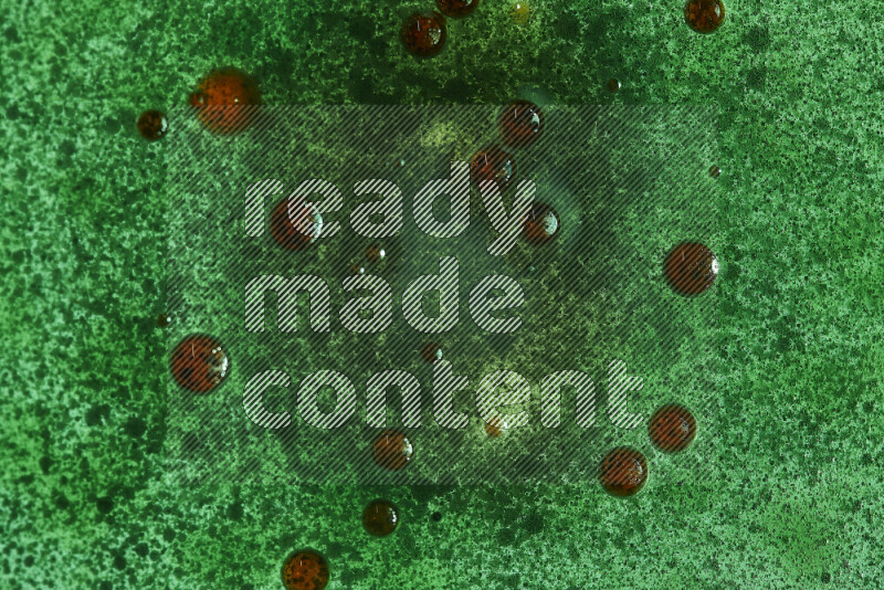 لقطات مقربة لقطرات ألوان مائية حمراء وخضراء على سطح الزيت على خلفية خضراء