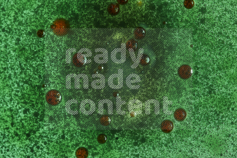 لقطات مقربة لقطرات ألوان مائية حمراء وخضراء على سطح الزيت على خلفية خضراء