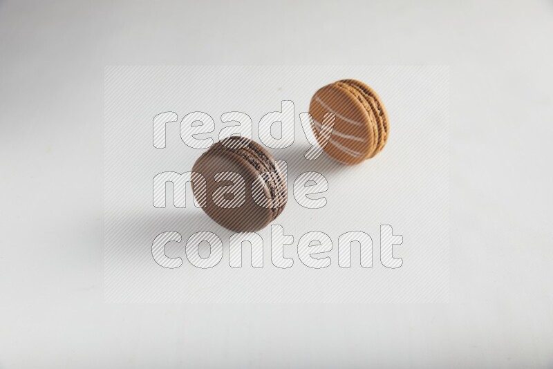 45º Shot of of two assorted Brown Irish Cream, and Brown Dark Chocolate macarons on white background