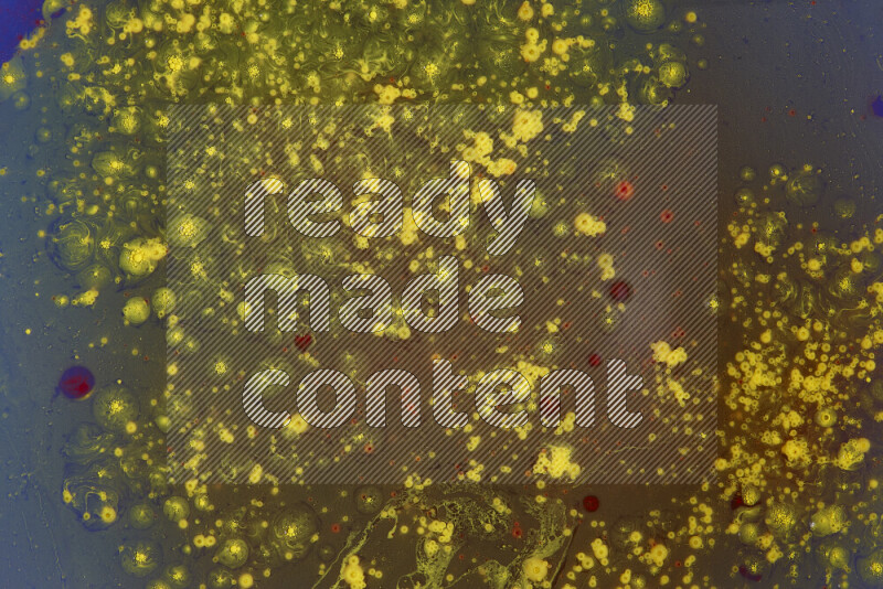 The image captures a dramatic splatter of yellow and red paints over an blue backdrop