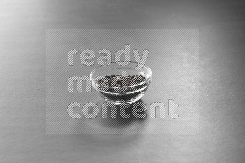 فلفل أسود في وعاء زجاجي علي خلفية سوداء