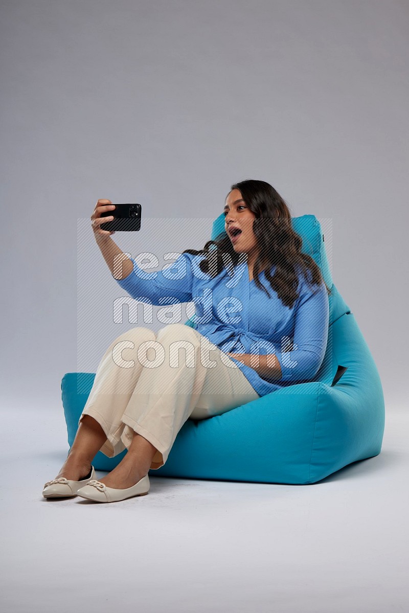 A woman sitting on a blue beanbag and taking selfie