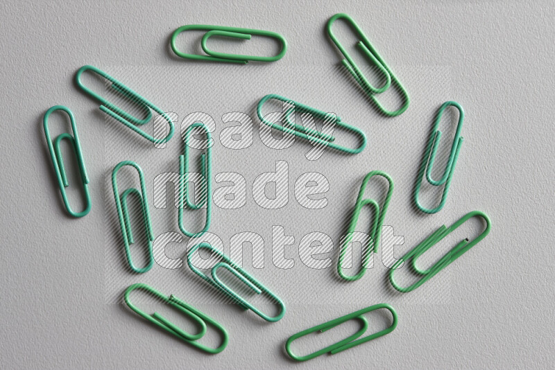Green paper clips isolated on a grey background
