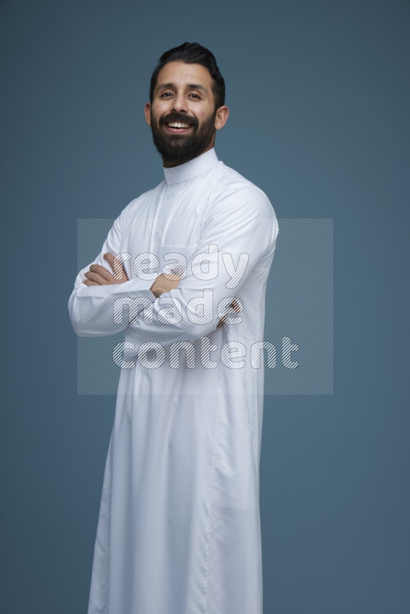 A man posing in a blue background wearing Saudi Thob