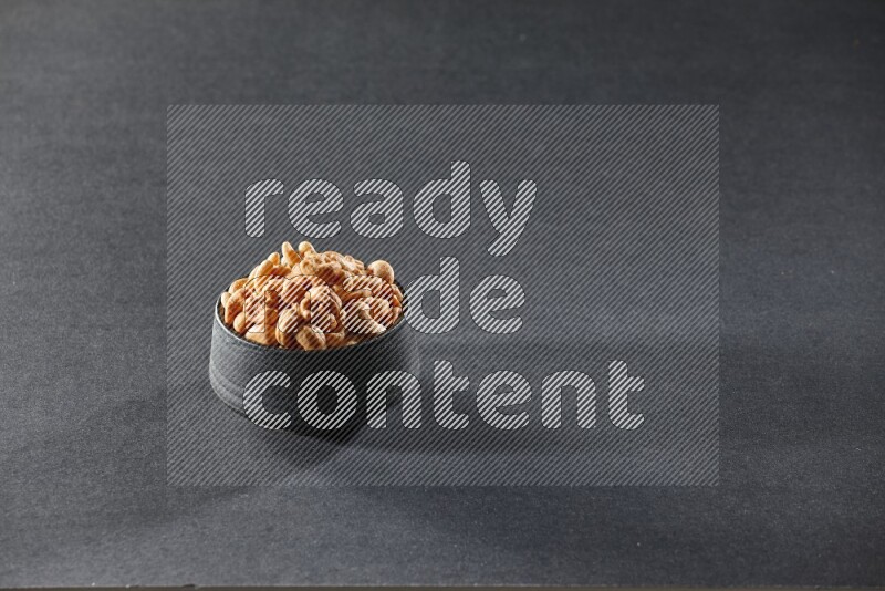 وعاء فخاري أسود ممتلئ بالكاجو على خلفية سوداء