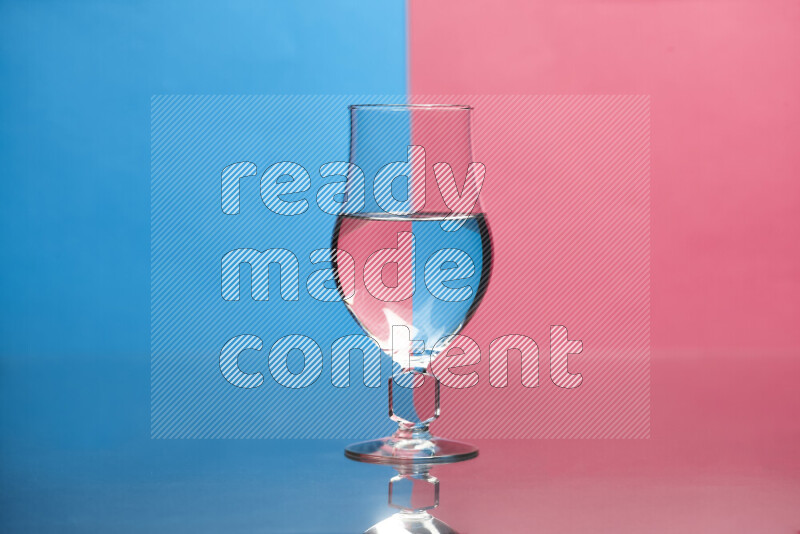 The image features a clear glassware filled with water, set against blue and pink background