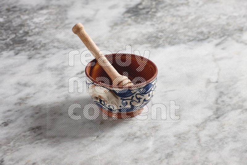 Decorative Pottery Pot with wooden honey handle in it, on grey marble flooring, 45 degree angle