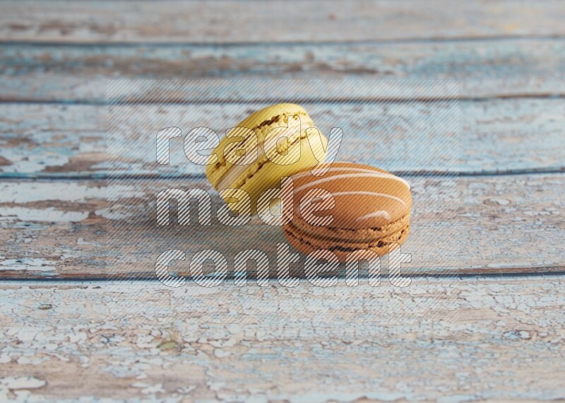 45º Shot of of two assorted Brown Irish Cream, and Yellow Lime macarons on light blue background