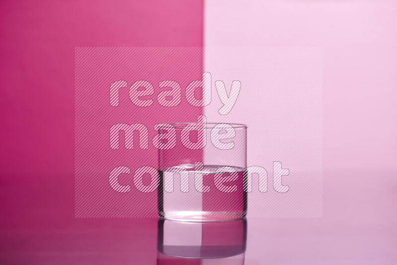 The image features a clear glassware filled with water, set against pink background