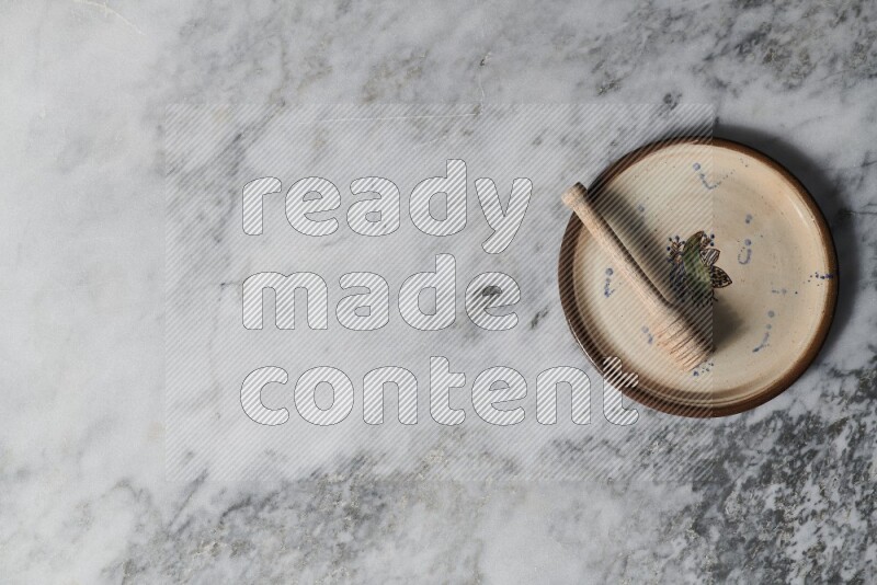 Decorative pottery plate with wooden honey dipper in it on grey marble background