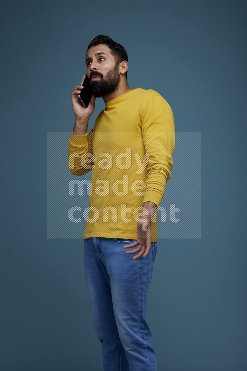 A man having a calling in a blue background wearing a yellow shirt