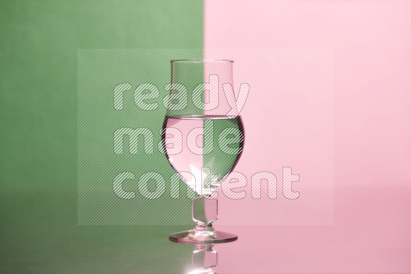 The image features a clear glassware filled with water, set against green and rose background