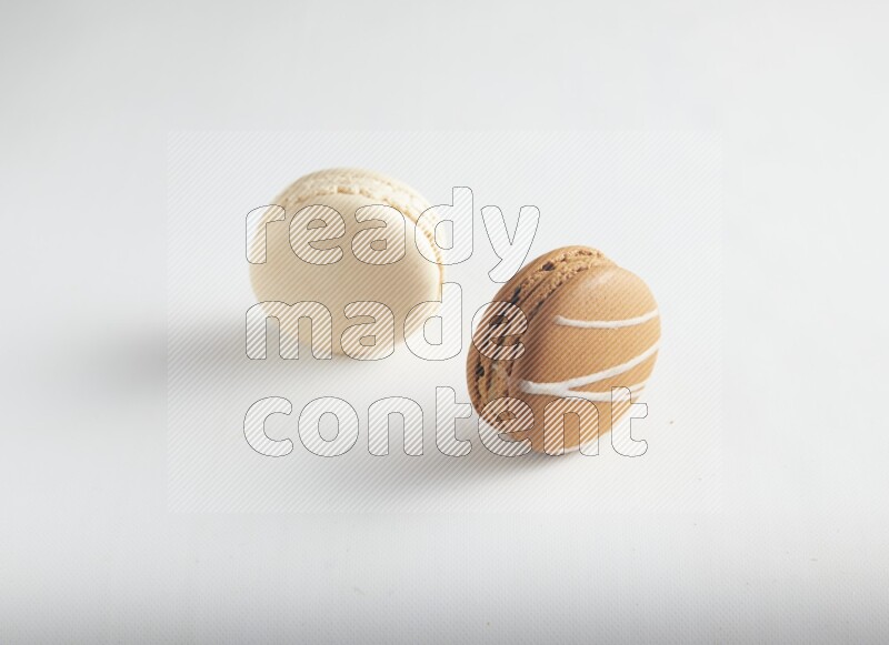 45º Shot of of two assorted Brown Irish Cream, and White Caramel fleur de sel macarons on white background