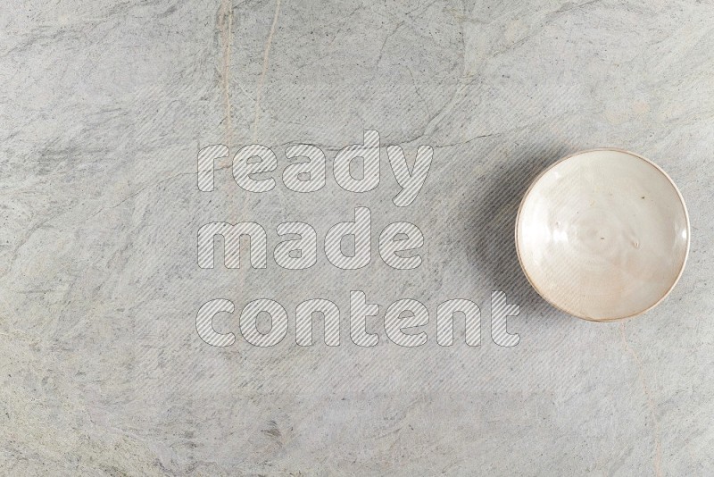 Top View Shot Of A Beige Pottery Plate On Grey Marble Flooring