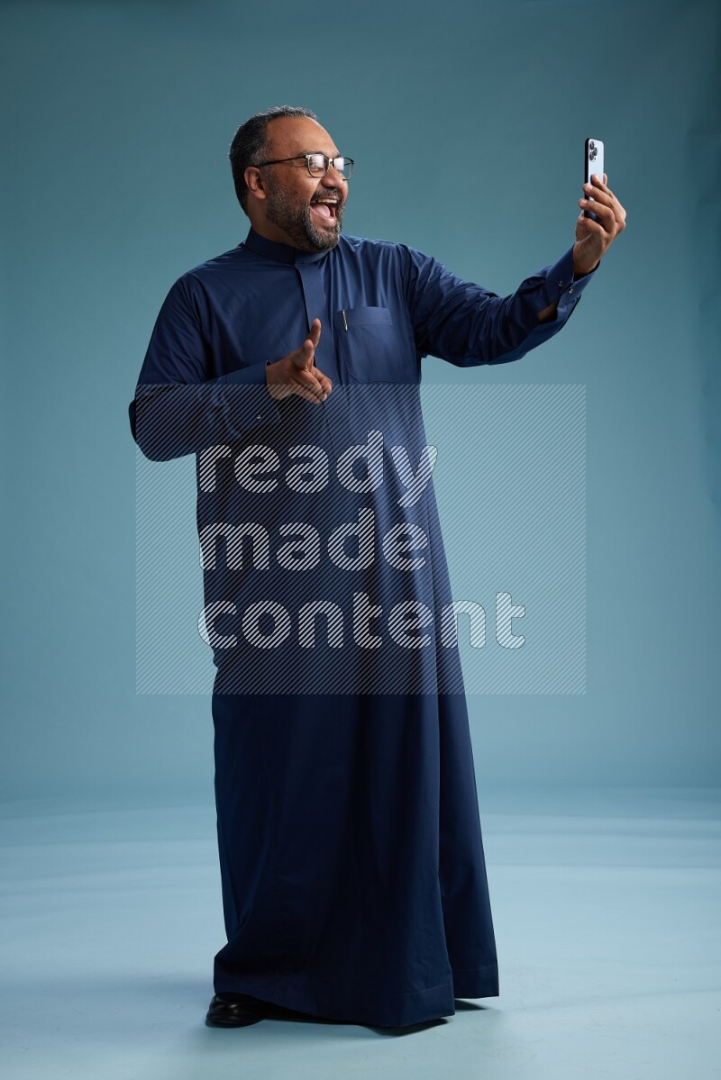 Saudi Man without shimag Standing taking selfie on blue background
