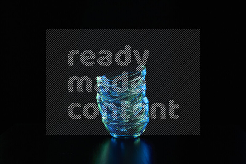 Glassware with rim light in blue and green against black background