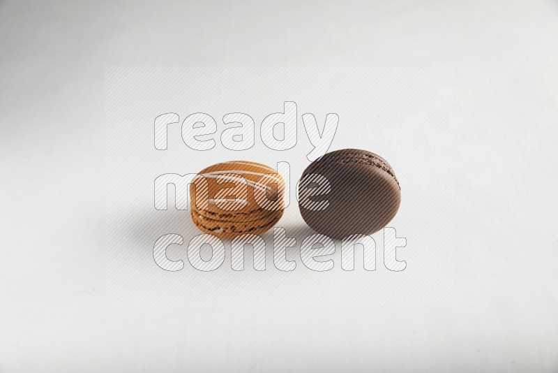 45º Shot of of two assorted Brown Irish Cream, and Brown Dark Chocolate macarons on white background