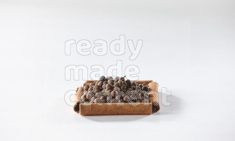 A single square of cinnamon sticks full of allspice on white flooring
