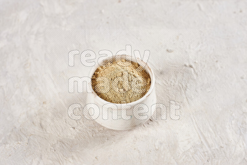 A beige pottery bowl full of ground ginger powder on white background