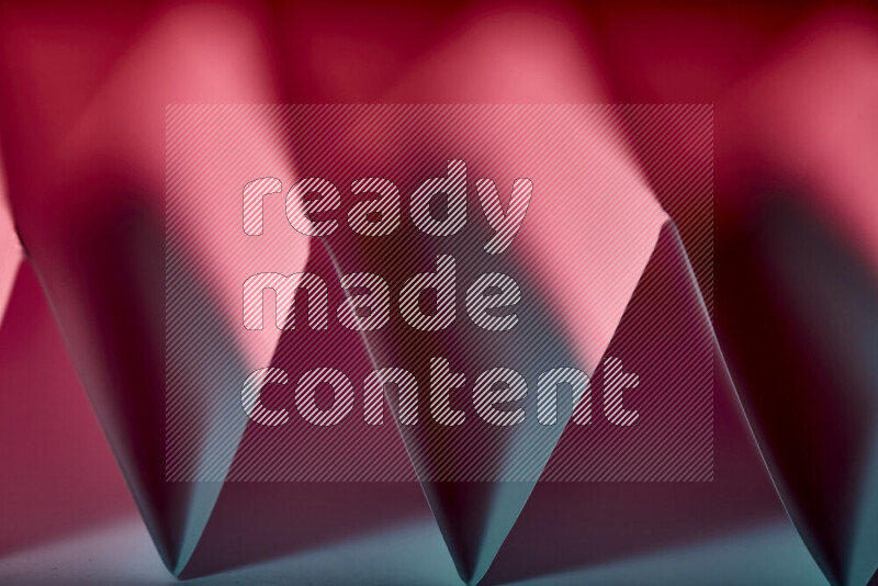 صورة مجردة مقربة تظهر طيات ورقية هندسية حادة بتدرجات اللون الأزرق والأحمر