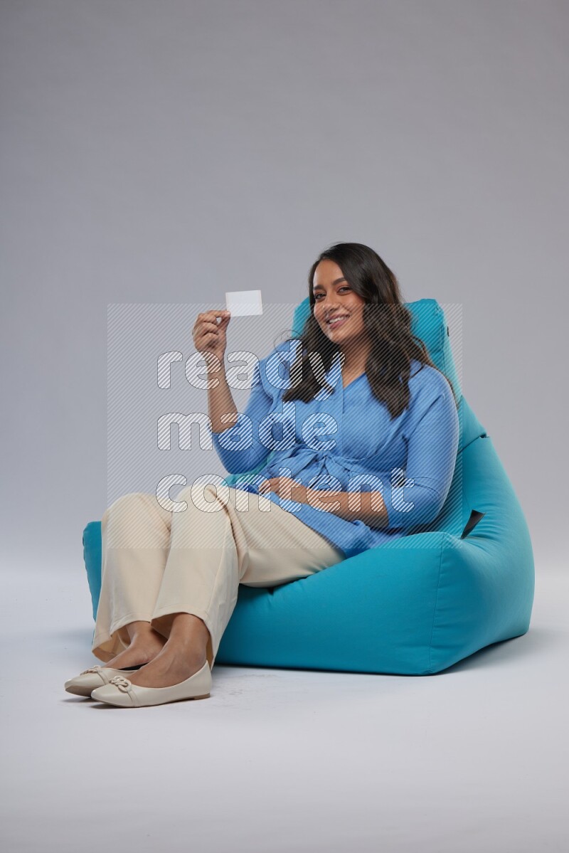 A woman sitting on a blue beanbag and holding ATM card