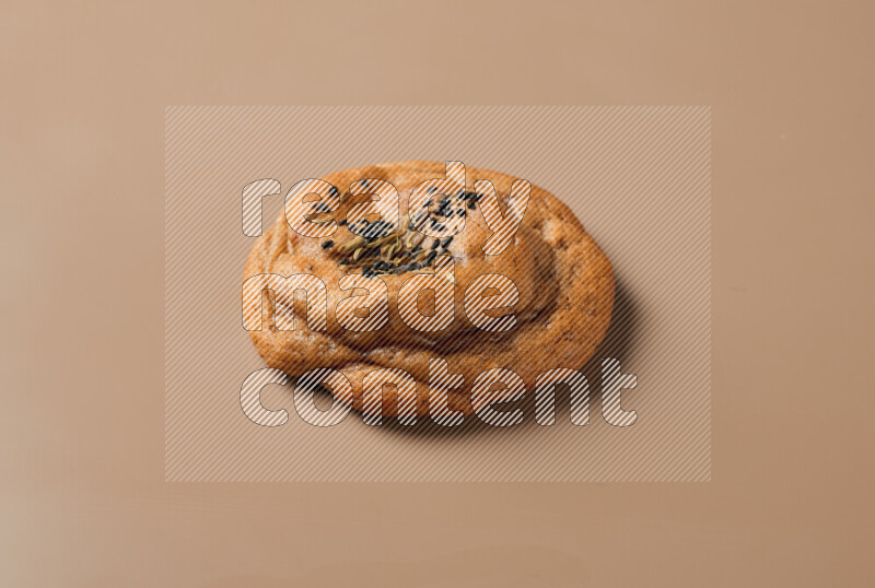 a whole Hasawi cookie with grains on a brown background