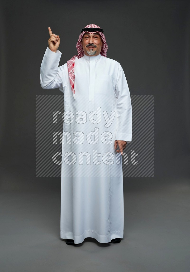 Saudi man with shomag Standing Interacting with the camera on gray background