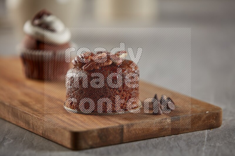 Chocolate cupcake topped with pecan on a wooden board