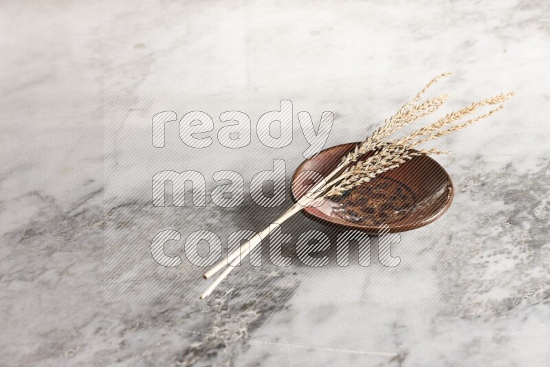 Wheat stalks on decorative pottery plate on grey marble background