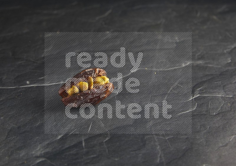 pistachios stuffed madjoul date on a black textured background