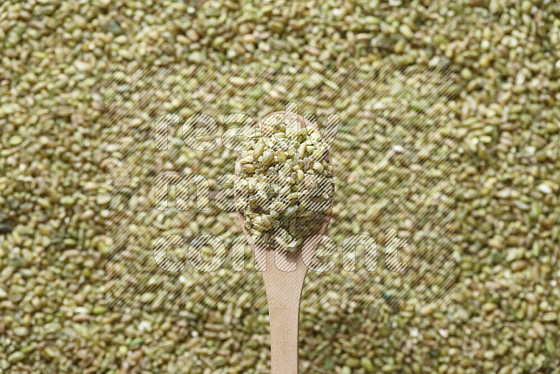 A wooden spoon full of freekeh on freekeh background