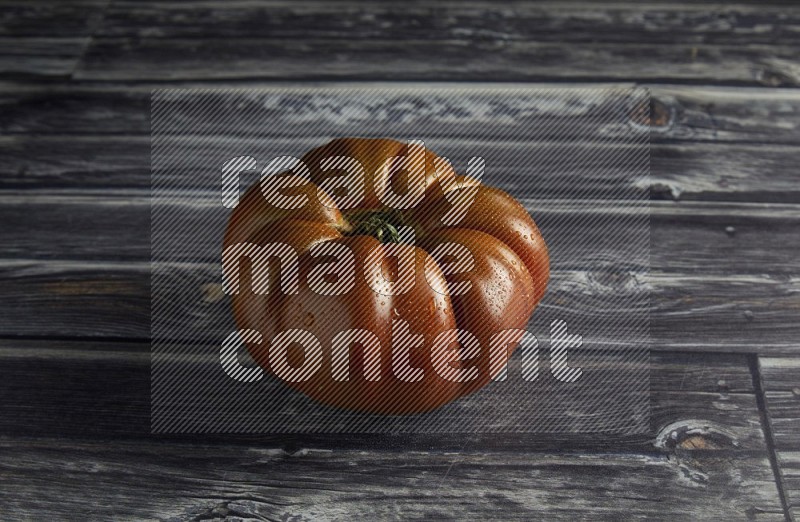 45 degree single heirloom tomato on a textured grey wooden background