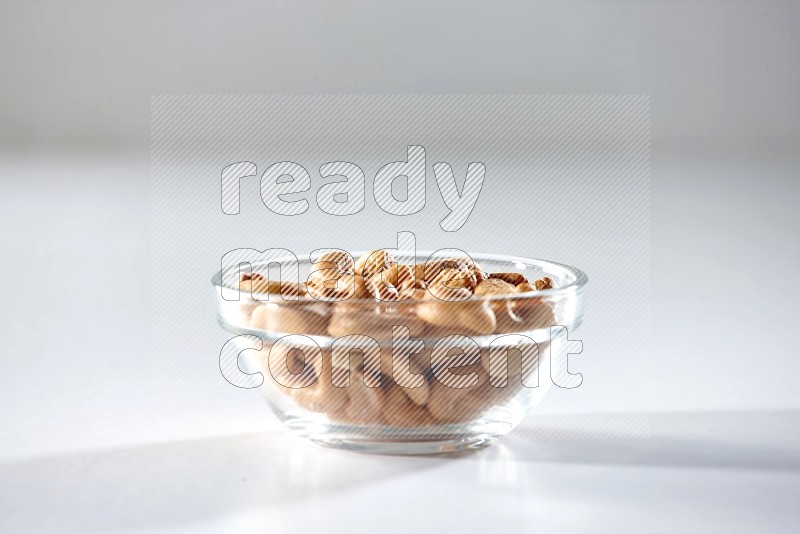 A glass bowl full of cashews on a white background in different angles