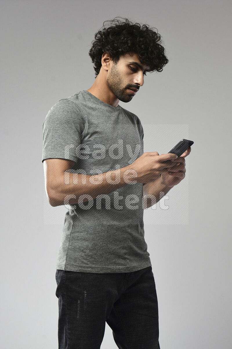 A man wearing casual standing and texting on the phone on white background