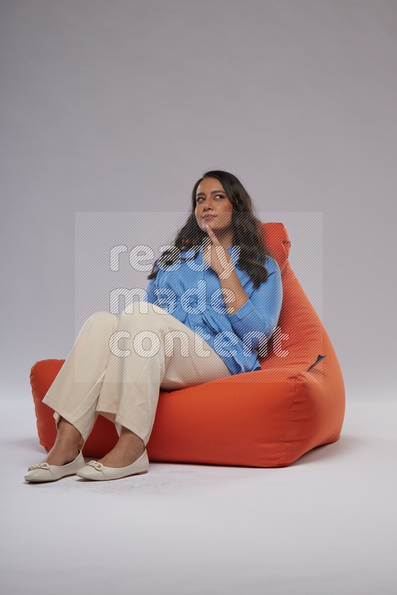 A woman sitting on an orange beanbag and interacting with the camera