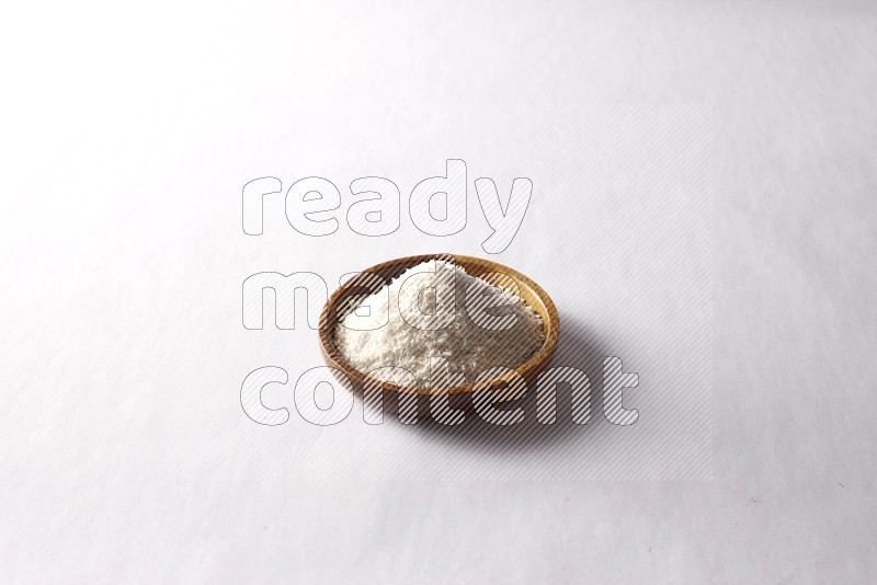 Desiccated coconuts in a wooden bowl on white background