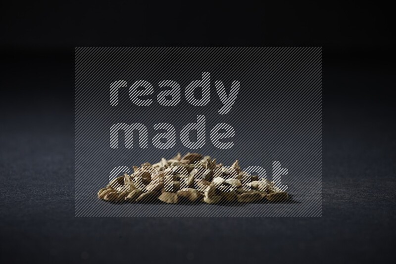 Cardamom in a triangle shape on black flooring