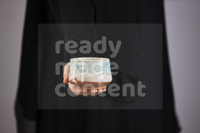 امرأة ترتدي عباءة سوداء تحمل أدوات فخارية مختلفة في أوضاع متعددة