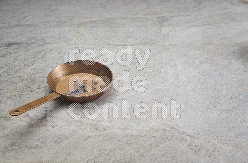 A Small Copper Pan On Grey Marble Flooring