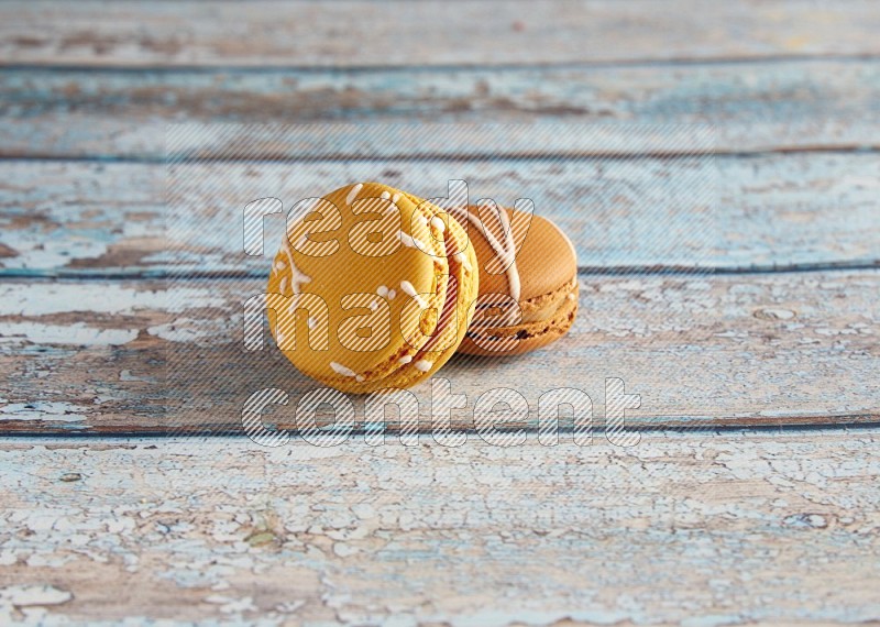 45º Shot of of two assorted Brown Irish Cream, and Yellow Piña Colada macarons on light blue background