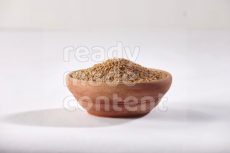 A wooden bowl full of mustard seeds on a white flooring in different angles