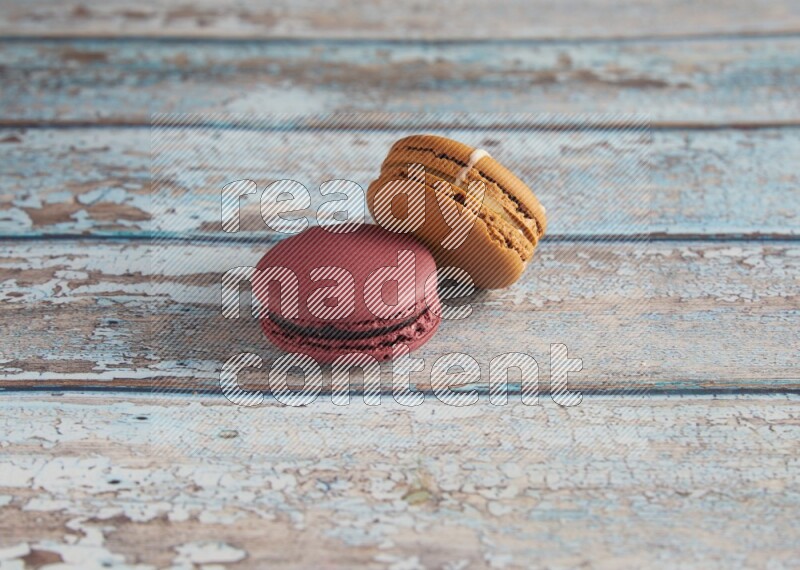 45º Shot of of two assorted Brown Irish Cream, and Red Cherry macarons  on light blue background