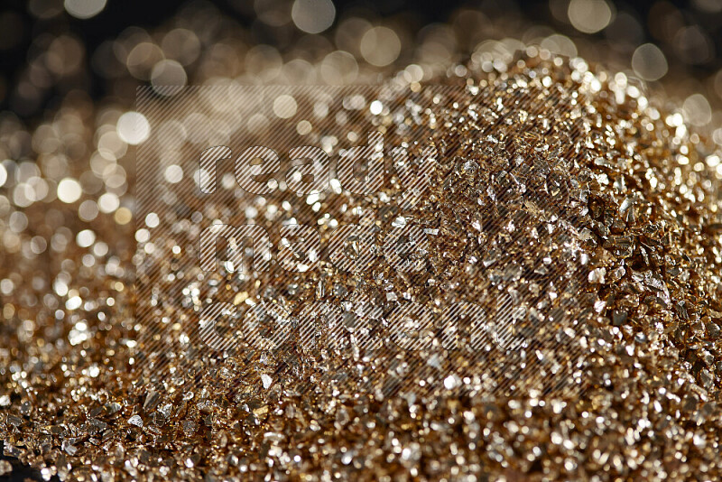 Gold shimmering fragments of glass scattered on a black background