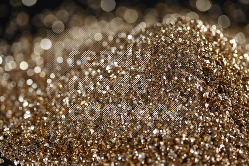 Gold shimmering fragments of glass scattered on a black background